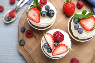 Sweet cupcakes with fresh berries on wooden table, flat lay