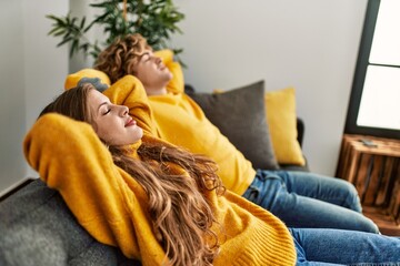 Obraz premium Young caucasian couple smiling confident relaxed with hands on head at home