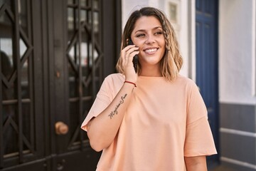 Young hispanic woman smiling confident talking on the smartphone at street