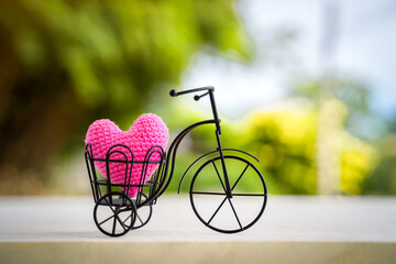 Vintage bicycle model with transport a pink heart on sunlight in the public park for supporting...