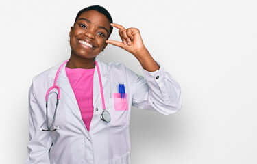 Young african american woman wearing doctor uniform and stethoscope smiling and confident gesturing with hand doing small size sign with fingers looking and the camera. measure concept.