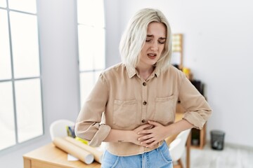 Young beautiful caucasian woman at construction office with hand on stomach because indigestion,...