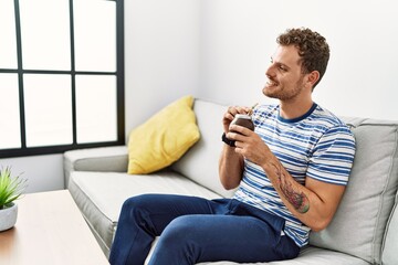 Young hispanic man smiling confident drinking mate at home