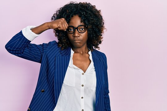 Young african american woman wearing business clothes and glasses strong person showing arm muscle, confident and proud of power