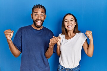 Young hispanic couple standing together celebrating surprised and amazed for success with arms...