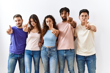 Obraz premium Group of young people standing together over isolated background pointing with finger up and angry expression, showing no gesture