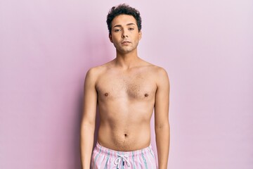 Fototapeta premium Young handsome man wearing swimwear shirtless relaxed with serious expression on face. simple and natural looking at the camera.