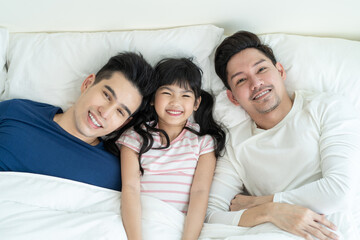 Portrait of handsome man gay family with young kid daughter in bedroom. 