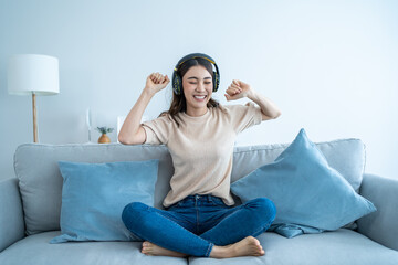 Asian funny woman listen to music and dance on floor in living room. 