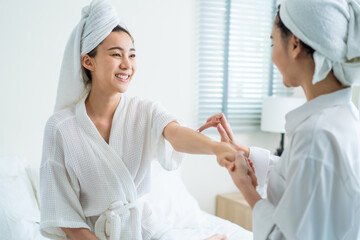 Obraz premium Asian lesbian gay couple enjoy put smooth and soft skin care on hands. 