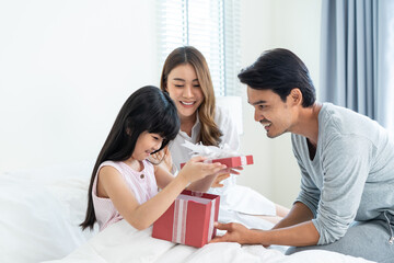 Asian lovely young little daughter open present gift box from parents. 