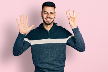 Young hispanic man with beard wearing casual winter sweater showing and pointing up with fingers...