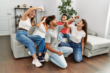 Group of young friends having party singing song using microphone at home.