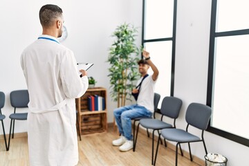 Naklejka na ściany i meble Two hispanic men doctor and patient at hospital waiting room
