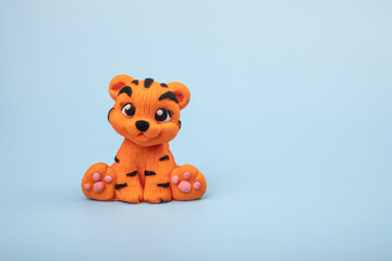 An orange tiger figurine on a blue background. The year 2022 is the year of the tiger according to the Eastern calendar.