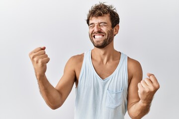 Young handsome man standing over isolated background very happy and excited doing winner gesture with arms raised, smiling and screaming for success. celebration concept.