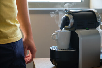 Unrecognizable man preparing coffee in a coffee machine with capsules.