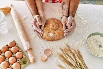 Young couple smiling happy cooking homemade bread at kitchen.