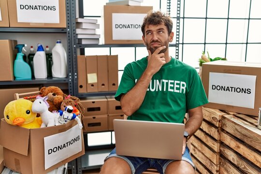 Young handsome man wearing volunteer t shirt using laptop thinking worried about a question, concerned and nervous with hand on chin