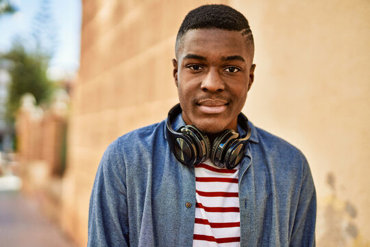 Young african american man with relaxed expression using headphones at the city.