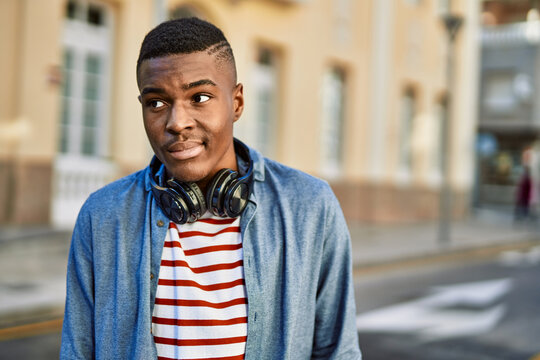 Young african american man with serious expression using headphones at the city.