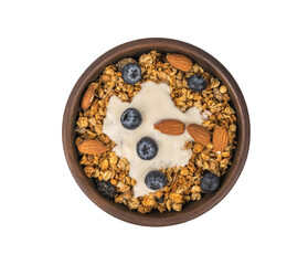 Muesli in a clay bowl with blueberries and nuts on a wooden table.