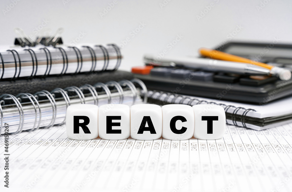 Poster on the table, among office objects, cubes with the inscription - react