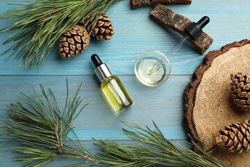 Pine essential oil, cones and branches on light blue wooden table, flat lay