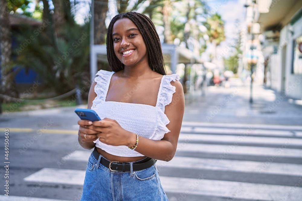 Poster Young african american girl smiling happy using smartphone at the city.