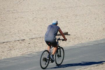 man riding bicycle on bike path along the coast
