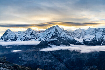 Fototapeta na wymiar View of the famous peaks Jungfrau, Mönch and Eiger from the mountain Schilthorn in the Swiss Alps Switzerland at sunrise with dramatic clouds and fresh snow.