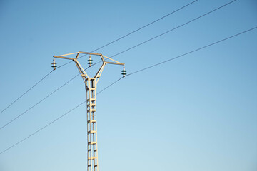 High voltage electricity line with a totally clear blue sky.