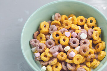 Multi colored cereal fruit loops in a bowl on gray background. Close up, copy space. Breakfast concept