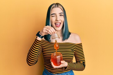 Young modern girl holding honey winking looking at the camera with sexy expression, cheerful and...