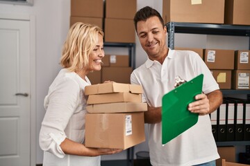 Middle age man and woman business partners reading checklist working at storehouse