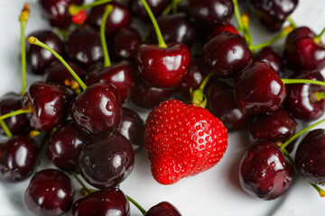 Cherries on a white plate with strawberries. Ripe cherry and strawberry fruits