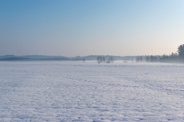 Landscape of winter in nature. Field covered the heavy snow with foot tracks on it near the forest in Europe.