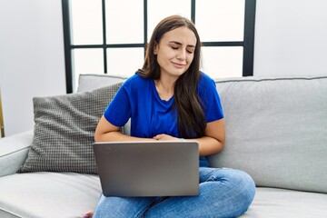 Fototapeta na wymiar Young brunette woman using laptop at home with hand on stomach because nausea, painful disease feeling unwell. ache concept.
