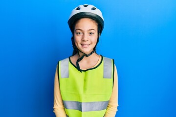 Beautiful brunette little girl wearing bike helmet and reflective vest with a happy and cool smile on face. lucky person.