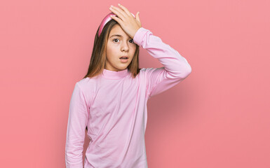 Beautiful brunette little girl wearing casual turtleneck sweater surprised with hand on head for mistake, remember error. forgot, bad memory concept.