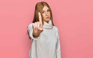 Young irish woman wearing casual winter sweater pointing with finger up and angry expression,...