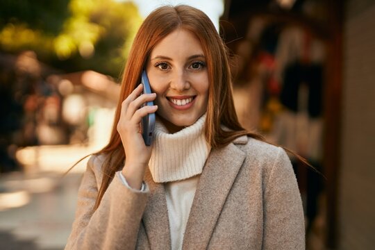 Young redhead girl smiling happy talking on the smartphone at the city.
