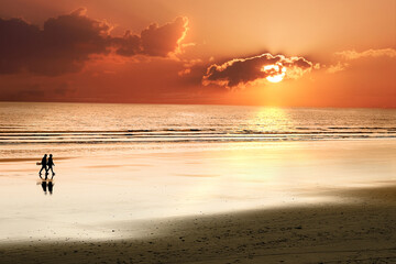 Senioren Paar spaziert am Strand bei Sonnenuntergang am Meer - Atlantik.