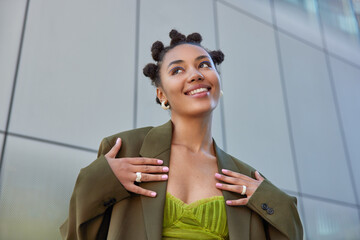 Cheerful good looking young woman with trendy hairstyle bright makeup dressed in dark green jacket...