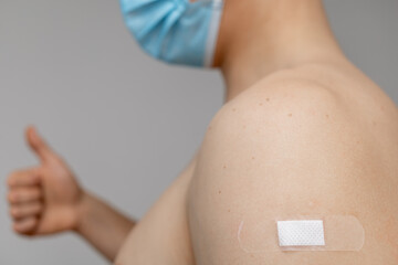 Man with patch on the shoulder showing thumbs up
