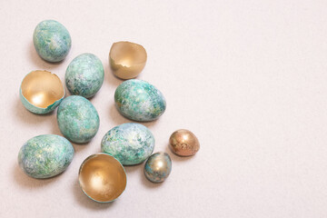 Stylishly colored Easter eggs. Inside of the golden shell, chicken and quail eggs are decorated with blue and turquoise paint, with non-uniform surface. Interesting idea for Easter decor. Copy space