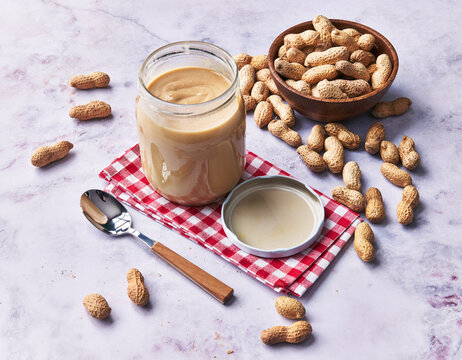  Bowl of peanuts with shell and peanut butter cream on a marble surface