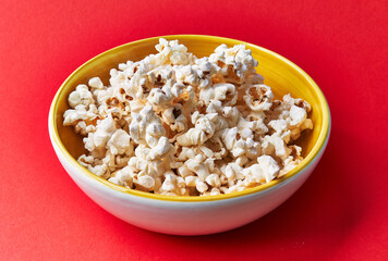  Bowl of salty popcorns on a red background