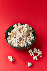  Bowl of salty popcorns on a red background