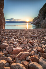 Hidden beach in Vrbnik on the island of Krk in Croatia. Beautiful stone beach between rocks and taken at sunrise.